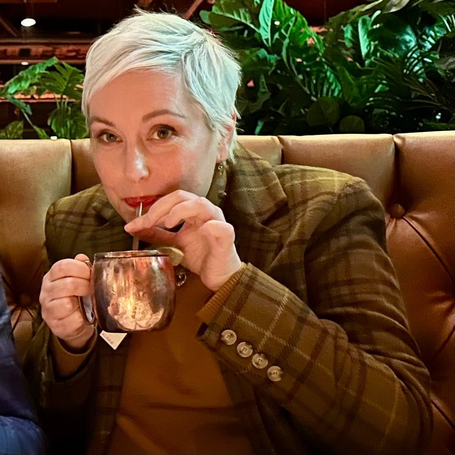 Woman drinking Moscow Mule in a restaurant that has been treated with a Tagged ALKAA sachet to avoid hangover symptoms.